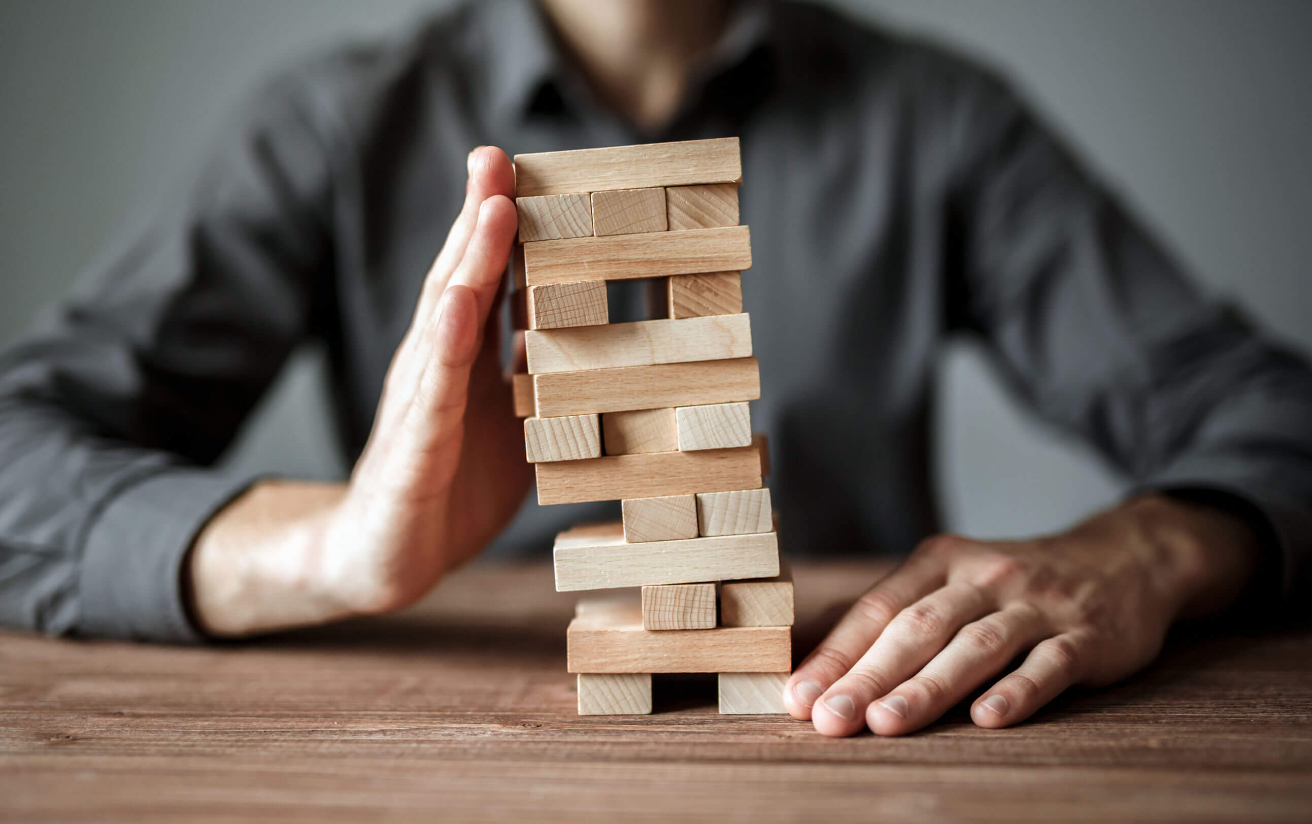 Un uomo sostiene una torre di Jenga con la mano