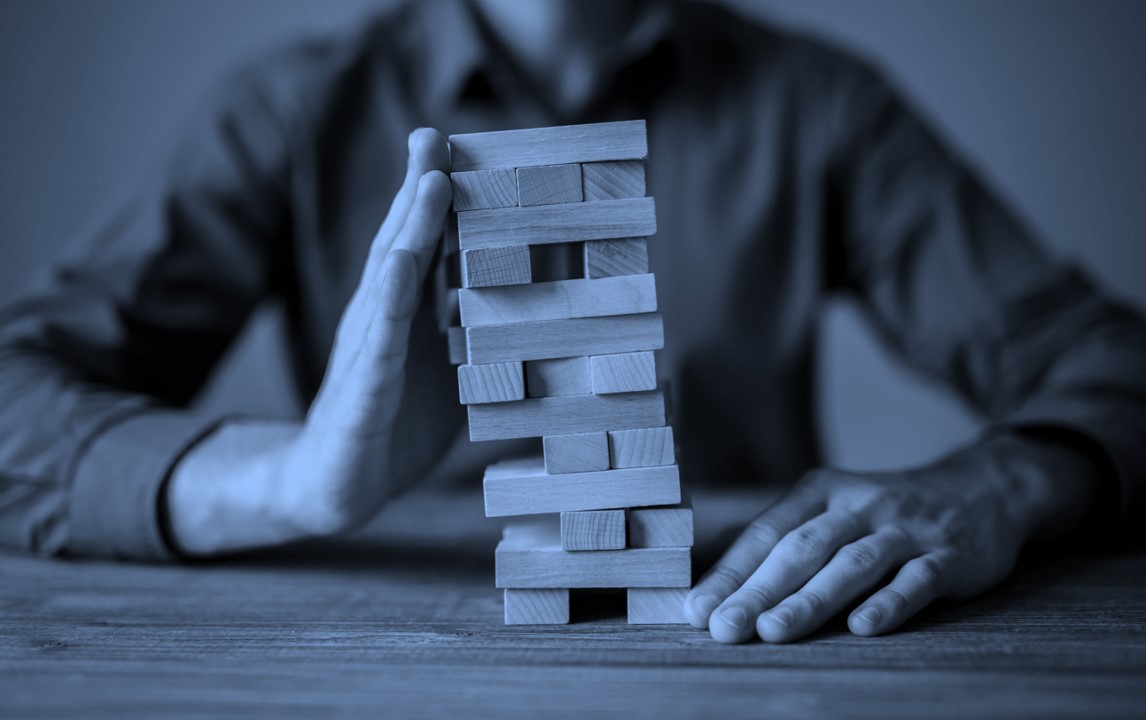 O homem apoia a torre Jenga com a sua mão