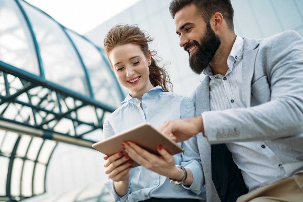 Un homme et une femme regardent une tablette à l'extérieur